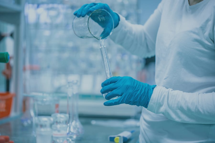 在制药环境中戴着手套拿着量杯的人