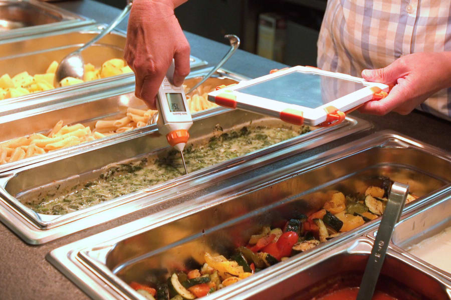 在自助餐厅使用手持测量设备测量温度 