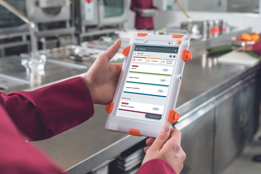 手持平板电脑，显示各种支票，背景是厨房