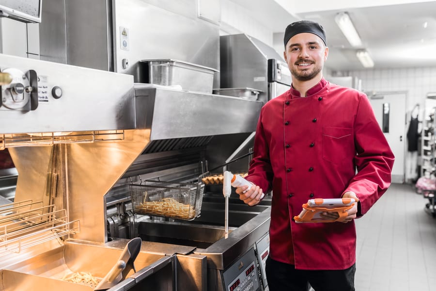 带着测量仪器在油炸锅前工作的员工