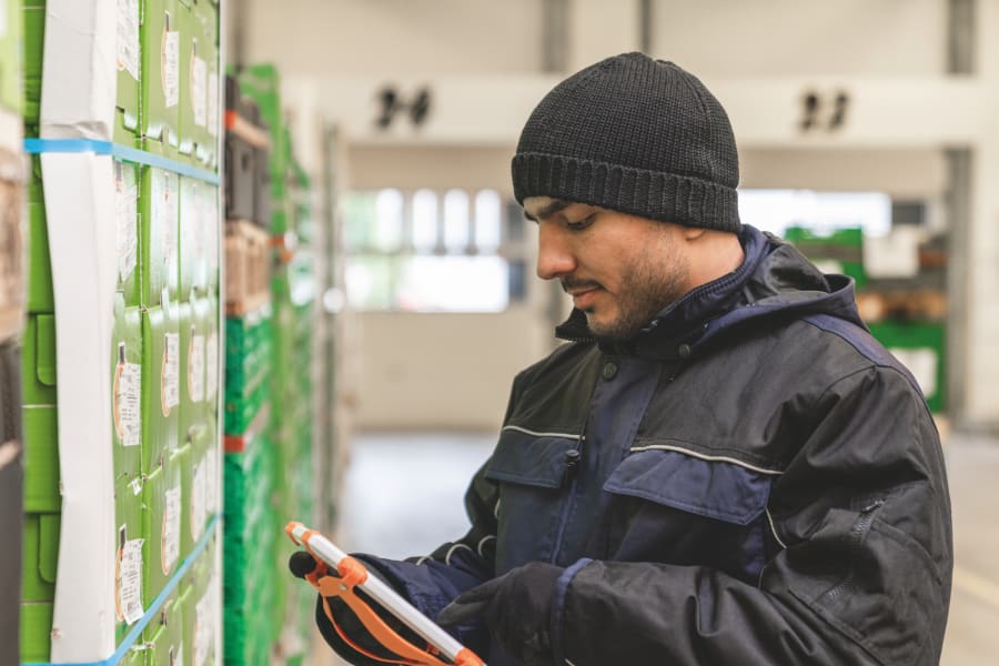 戴帽子的员工拿着平板电脑在检查什么
